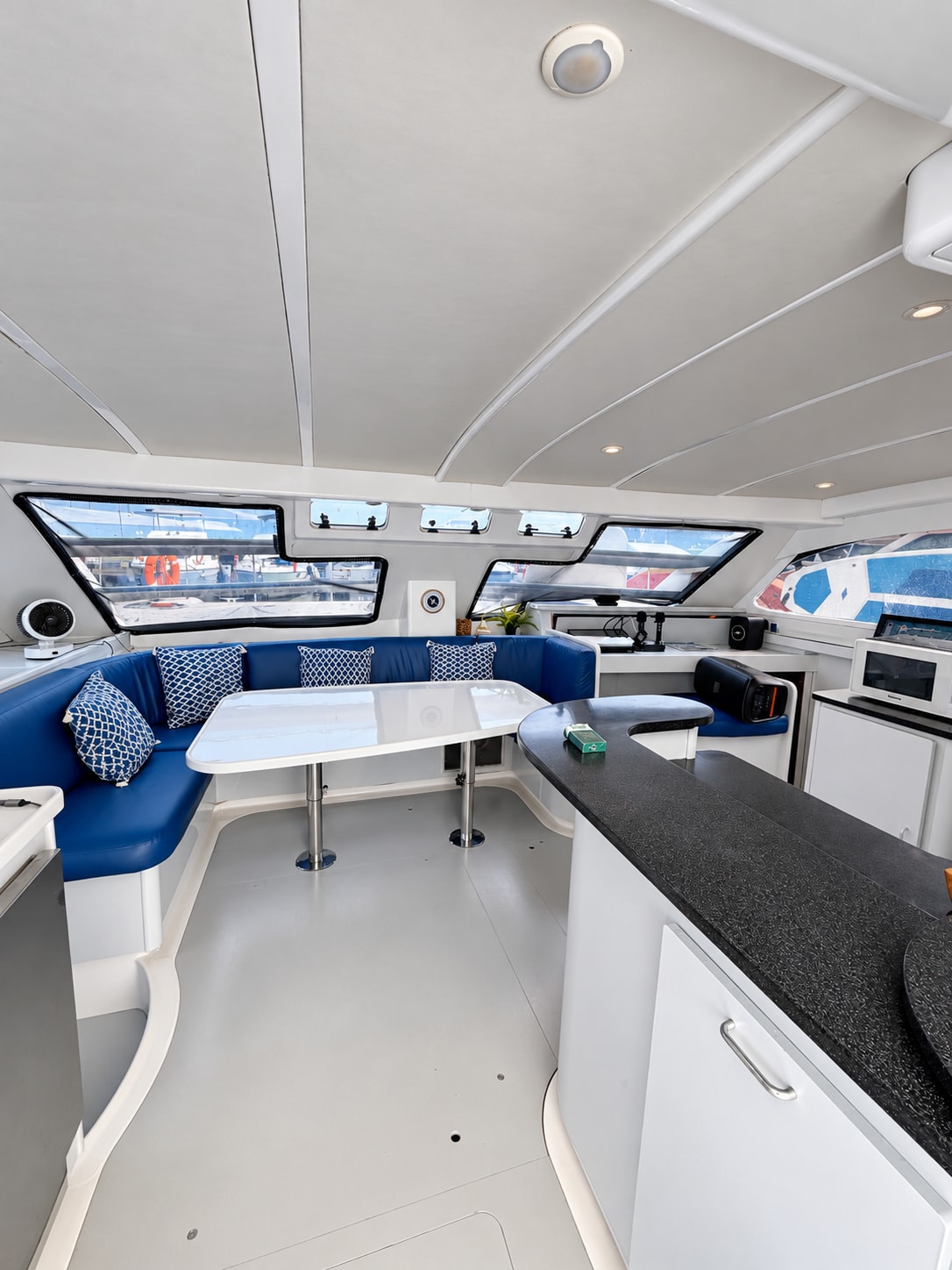 One Lotus yacht — Interior lounge with blue seating and galley
